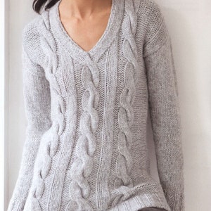 May include: A grey cable knit sweater with a v-neck.