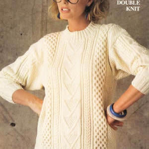Può includere: Un maglione di lana bianco con un motivo a treccia e un design a maglia doppia. Il maglione ha un collo rotondo e maniche lunghe.