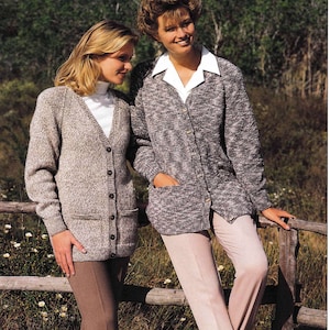 Könnte beinhalten: Zwei Frauen tragen langärmelige, geknöpfte Strickjacken mit einem gesprenkelten Muster. Die Jacke links ist in einem helleren Braunton gehalten, während die Jacke rechts eine dunklere graue Farbe hat. Beide Frauen tragen Hosen.