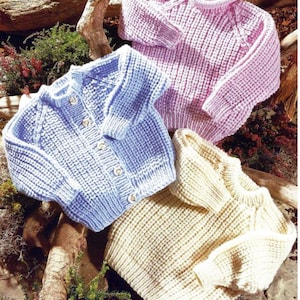 Puede incluir: Tres cárdigans de punto para bebé en diferentes colores: azul claro, rosa y crema. Los cárdigans tienen un diseño sencillo con cuello redondo y cierre de botones.