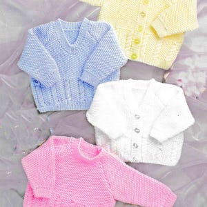 Peut inclure: Quatre pulls pour bébés tricotés en couleurs pastel : jaune, bleu, blanc et rose. Le pull jaune a des boutons. Les pulls bleus et roses ont un motif en tricot torsadé sur le devant. Le pull blanc a un col en V.