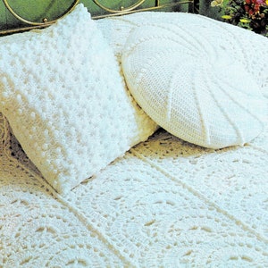 May include: A white crocheted bedspread with a white crocheted pillow and a white crocheted round pillow. The bedspread has a delicate floral pattern.
