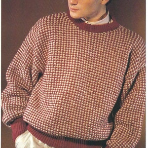 Puede incluir: Un suéter de punto rojo y blanco con cuello redondo. El suéter tiene un dobladillo y puños de canalé.