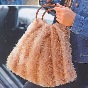 Op de afbeelding: Een bruine, pluche tote bag met houten handvatten. De tas is gemaakt van een zacht, pluche materiaal en heeft een ontspannen, casual look.