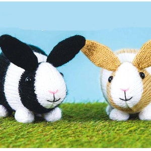 Puede incluir: Dos conejos de peluche tejidos. Uno es blanco y negro con rayas, el otro es marrón y blanco con rayas. Ambos tienen caras blancas y narices rosas.