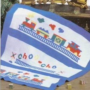 Può includere: Una copertina per neonati in maglia con uno sfondo a strisce blu e bianco. La copertina presenta un treno con vagoni colorati e le parole "choo-choo" su di essa.