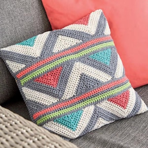 May include: A gray, white, teal, green, and coral crocheted pillow with a geometric pattern.