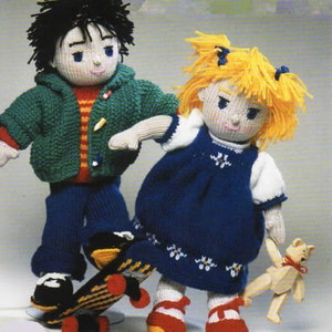 Puede incluir: Dos muñecas de punto, una con cabello negro que lleva una chaqueta verde y pantalones vaqueros azules, de pie sobre una patineta, y la otra con cabello rubio que lleva un vestido azul y calcetines blancos, sosteniendo una muñeca de madera.