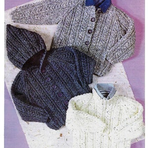 May include: Three knitted sweaters in different colors and patterns. The sweaters are laid out on a light brown surface. The sweaters have a cable knit pattern.