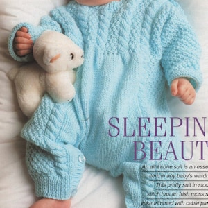 May include: A light blue knitted baby sleeper with a cable knit yoke and a white teddy bear. The sleeper has button closures at the shoulders and feet. "SLEEPIN BEAUT" is written in purple text at the bottom of the image. "An all-in-one suit is an essential item in any baby's wardrobe. This pretty suit in stockinette stitch has an Irish moss stitch yoke trimmed with cable panels."