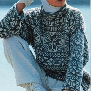Puede incluir: Una mujer con un gorro blanco de punto y un suéter con estampado azul y blanco. Lleva guantes blancos y botas blancas.