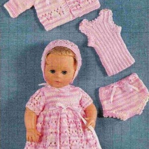 May include: A pink knitted doll outfit with a dress, cardigan, hat, vest, and bloomers. The outfit is made with a pink and white yarn.