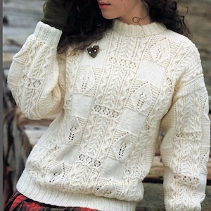 May include: A white knitted jumper with a delicate cable knit pattern and a round neckline.