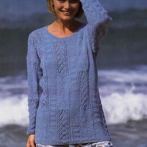 Op de afbeelding: Een lichtblauwe gebreide trui met een delicaat kantpatroon. De trui heeft een ronde hals en lange mouwen.