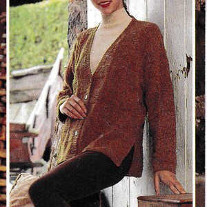 May include: A brown knitted cardigan with a V-neck and a button closure. The cardigan is worn over a white turtleneck shirt and brown pants.