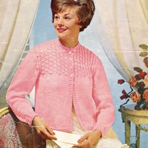 Peut inclure: Un cardigan rose en tricot avec une fermeture boutonnée et un motif texturé sur le devant. Le cardigan a des manches longues et un col rond.