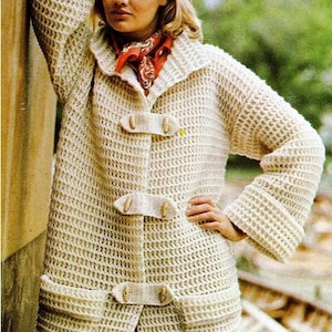 Può includere: Un cardigan bianco lavorato a maglia con un ampio collo, maniche lunghe e chiusura con bottoni. Il cardigan ha due grandi tasche sul davanti e una trama a nido d'ape.