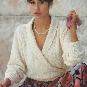 Könnte beinhalten: Eine Frau trägt einen weißen Strickpullover mit tiefem V-Ausschnitt und einen Rock mit Blumenmuster. Sie trägt eine Perlenkette und einen Perlenohrring.