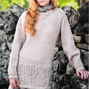 May include: A light pink knitted jumper with a cable knit pattern on the sleeves and bottom hem. The jumper has a round neckline and is made of a soft, textured yarn.