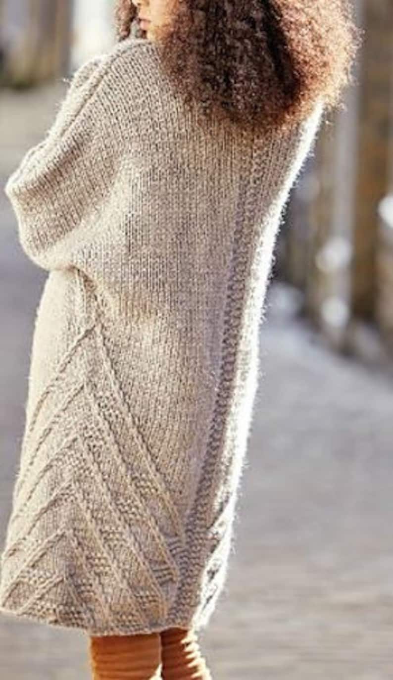 Pu&ograve; includere: Un lungo cardigan di maglia beige con un motivo a treccia. Il cardigan ha una vestibilit&agrave; ampia e una forma lunga e fluida.