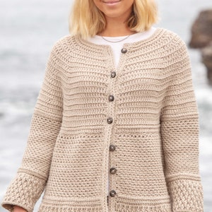 Può includere: Un cardigan beige lavorato a uncinetto con chiusura a bottoni e orli e polsini a coste.