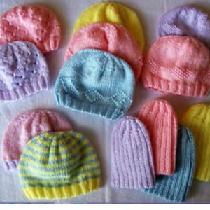 Puede incluir: Una colección de gorros de bebé tejidos en varios colores, incluyendo rosa, morado, azul y amarillo. Los gorros están hechos con una variedad de puntadas y patrones.