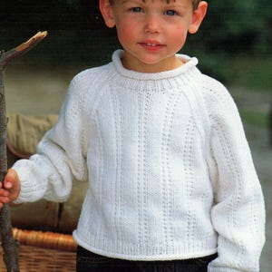 May include: A white knitted jumper with a round neckline and long sleeves. The jumper has a delicate openwork pattern.