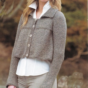 May include: A brown knitted cardigan with a white collared shirt underneath. The cardigan has a button-up front and long sleeves.