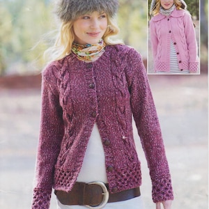 May include: A woman wearing a pink and white cable knit cardigan with a fur hat and a brown leather belt. The cardigan has a button closure and a ribbed collar.