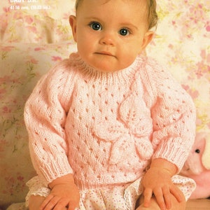 May include: A pink knitted baby sweater with a floral design. The sweater is made with a delicate open stitch pattern and has a round neckline. The sweater is suitable for babies aged 41-56 cm (16-22 inches).