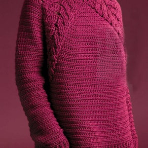 May include: A deep pink crocheted sweater with a cable knit design on the shoulders and sleeves.