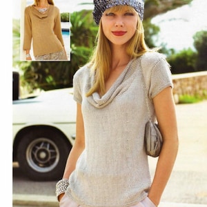 May include: A woman wearing a light grey cowl neck sweater with short sleeves and a sequined hat. She is wearing a light pink skirt and a silver bracelet.