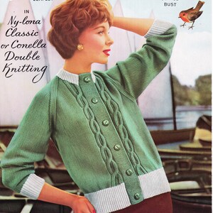 Puede incluir: Un cárdigan verde de punto de cable con ribetes y botones blancos. El cárdigan lo lleva una mujer con el pelo rojo y un cuello blanco. El texto "Ny-lona Classic o Conella Double Knitting" es visible en la imagen.