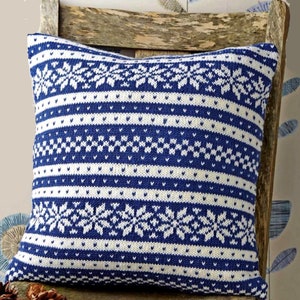 May include: A blue and white knitted throw pillow with a snowflake pattern. The pillow is sitting on a wooden chair.