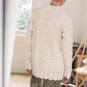 Op de afbeelding: Een witte gebreide trui met een kabelbreipatroon en een delicaat kantontwerp. De trui heeft een ontspannen pasvorm en een iets langere lengte.