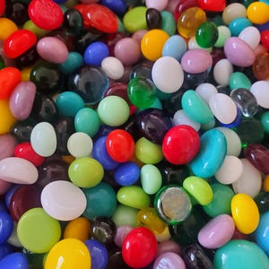 Könnte beinhalten: Eine große Sammlung bunter Glassteine in verschiedenen Formen und Größen. Die Steine sind eine Mischung aus Rot, Grün, Blau, Gelb, Lila und Weiß.