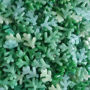 May include: A close-up image of a large pile of green and light green plastic coral reef pieces. The pieces are shaped like branches with multiple points.