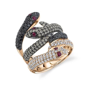 Könnte beinhalten: Ein Ring aus Roségold mit drei ineinander verschlungenen Schlangen, die jeweils mit schwarzen, braunen und weißen Diamanten besetzt sind. Die Augen der Schlangen sind mit Rubin-Steinen akzentuiert.