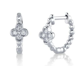 May include: A pair of silver hoop earrings with a small, four-leaf clover design set with clear diamonds.