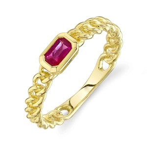 May include: A gold ring with a red gemstone set in a rectangular bezel. The ring band is a twisted chain design.