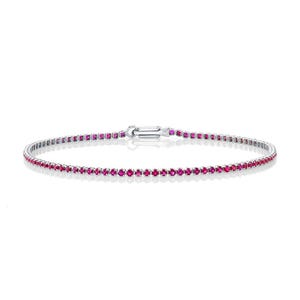 May include: A delicate silver tennis bracelet with a row of small, bright pink ruby stones.