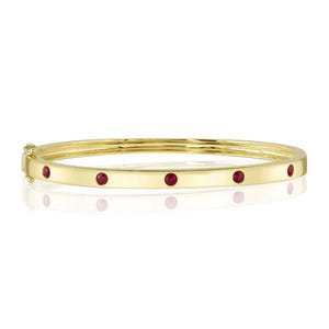 May include: A gold bangle bracelet with five red gemstones set into the band.