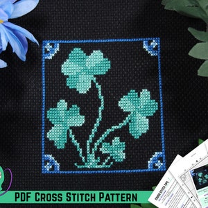 May include: A PDF cross stitch pattern for a shamrock design. The pattern features a black background with a blue border and green shamrocks.