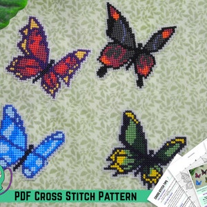 May include: Four colorful butterfly cross stitch patterns. The butterflies are red, blue, black, and green. The patterns are printed on white paper and include instructions for stitching.