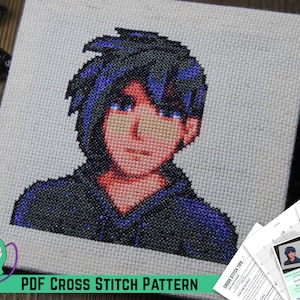 May include: A cross stitch pattern of a pixelated portrait of a person with blue hair and a black shirt. The pattern is on a white canvas and is surrounded by dice.