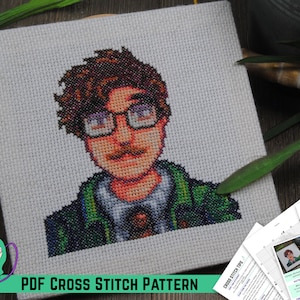 May include: A PDF cross stitch pattern featuring a pixelated portrait of a person with brown hair, a mustache, and glasses wearing a green jacket and a tie. The pattern includes instructions and a color key.