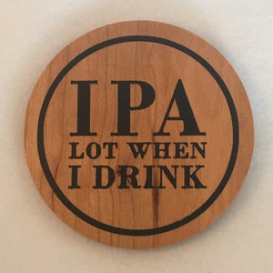 May include: A round wooden coaster with a black border and the text "IPA LOT WHEN I DRINK" in black lettering.