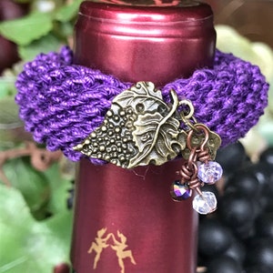 May include: Purple crocheted wine bottle stopper with a grapevine charm and crystal beads.