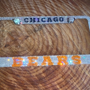May include: A silver license plate frame with clear rhinestones and the words "CHICAGO BEARS" in orange rhinestones.
