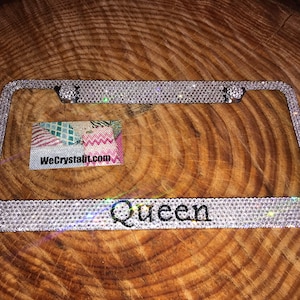 May include: A silver license plate frame covered in clear rhinestones with the word "Queen" in the center.
